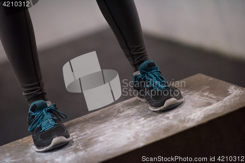 Image of black woman is performing box jumps at gym