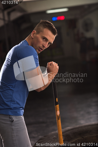 Image of man workout with hammer and tractor tire