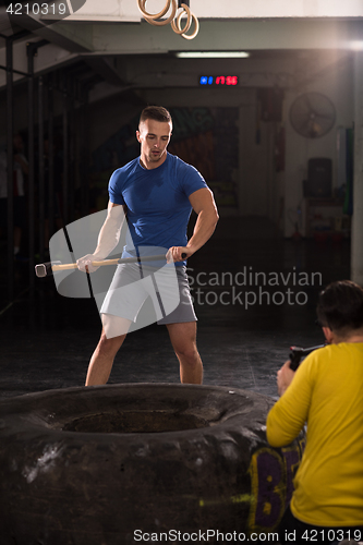 Image of man workout with hammer and tractor tire