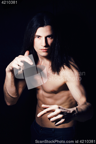 Image of handsome young man with long hair naked torso on black backgroun