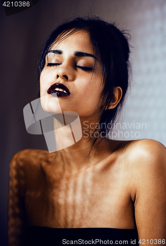 Image of pretty brunette woman with make up like demon at halloween, closeup scary background concept