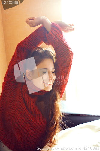 Image of young pretty real woman in red sweater and scarf all over her fa