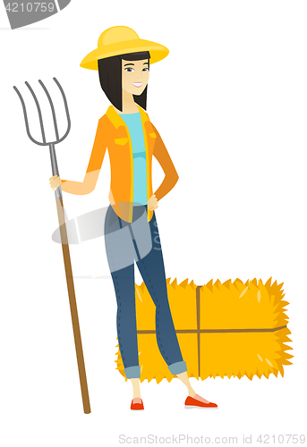 Image of Young asian farmer holding a pitchfork.