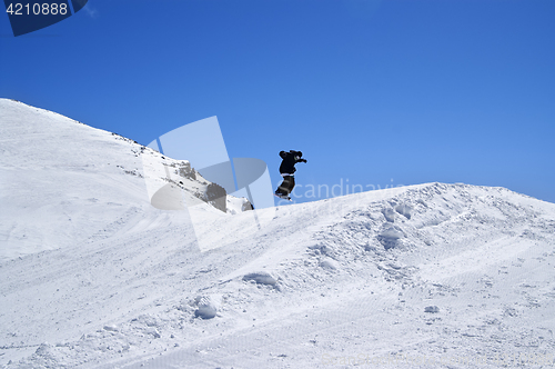 Image of Snowboarder jumping in snow park at ski resort on sun winter day