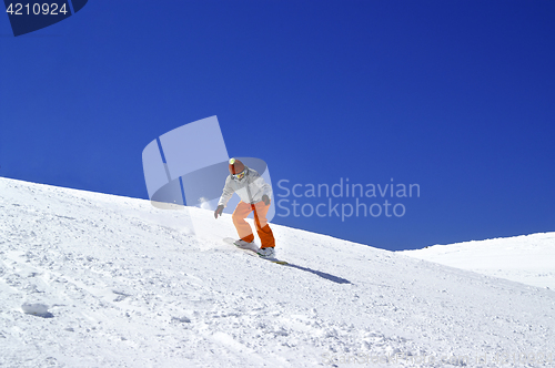 Image of Snowboarder downhill in terrain park and blue clear sky