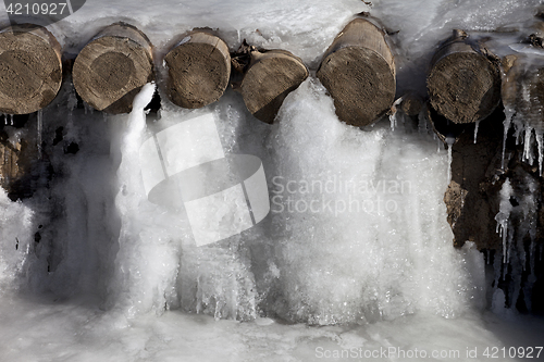 Image of Icy mountain stream and wooden bridge frozen into ice
