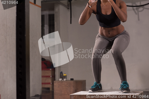 Image of black woman is performing box jumps at gym