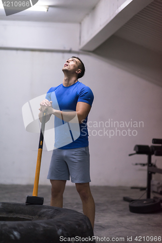 Image of man workout with hammer and tractor tire