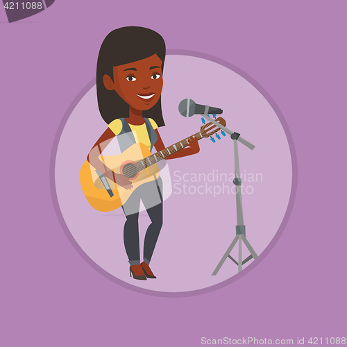 Image of Woman singing in microphone and playing guitar.