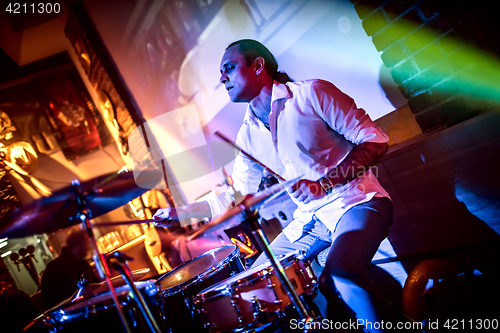 Image of Drummer playing on drum set on stage.