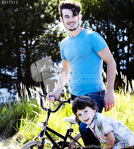 Image of father learning his son to ride on bicycle outside, real happy f