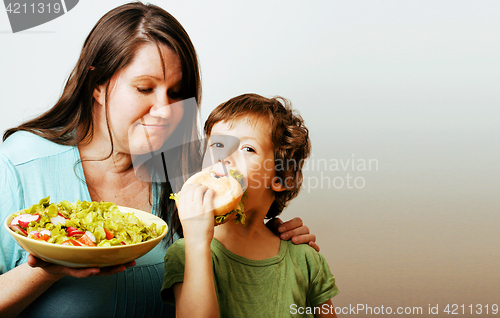 Image of mature woman holding salad and little cute boy with hamburger te