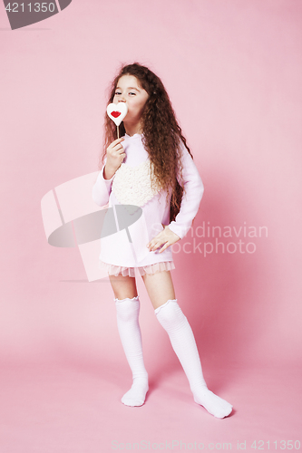 Image of little cute girl with candy on pink background posing emotional, lifestyle people concept 
