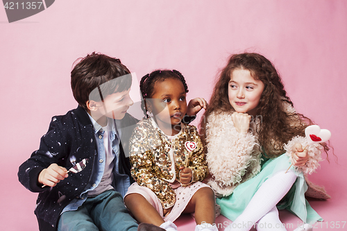 Image of lifestyle people concept: diverse nation children playing together, caucasian boy with african little girl holding candy happy smiling 