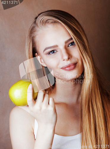Image of young pretty blond woman with green apple happy cheerful smiling