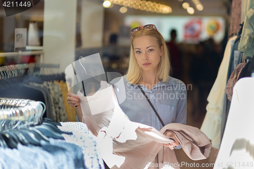 Image of Beautiful woman shopping fashionable clothes in clothing store.