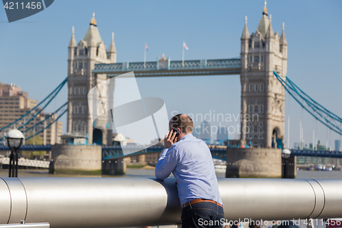 Image of British businessman talking on mobile phone outdoor in London city, UK.