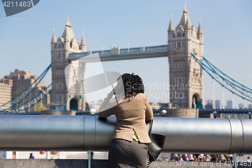 Image of British businesswoman talking on mobile phone outdoor in London city, UK.