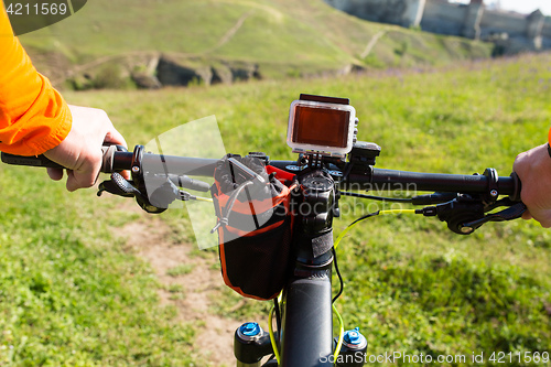 Image of Hands in orange jacket holding handlebar of a bicycle