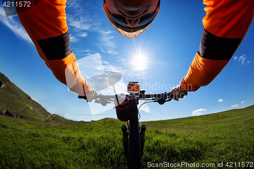 Image of Hands in orange jacket holding handlebar of a bicycle