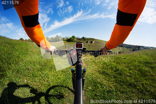 Image of Hands in orange jacket holding handlebar of a bicycle