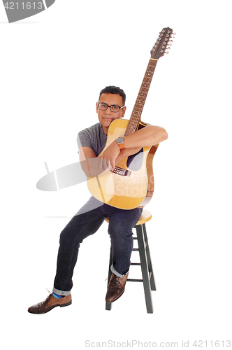 Image of Hispanic mal sitting with his guitar.