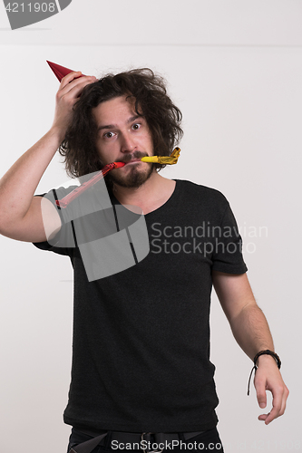 Image of Portrait of a man in party hat blowing in whistle