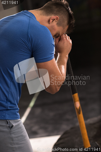 Image of man workout with hammer and tractor tire