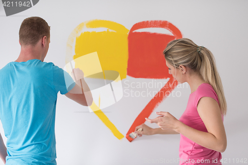 Image of couple are painting a heart on the wall