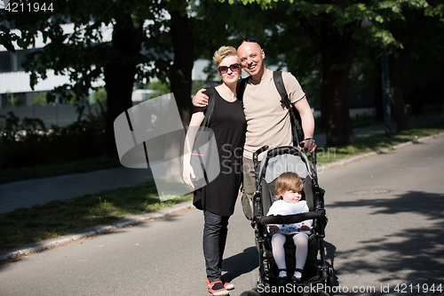 Image of couple with baby pram in summer park