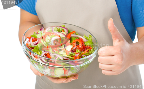 Image of Cook is holding a big bowl with fresh salad