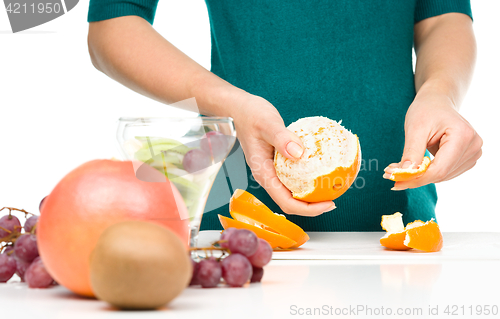 Image of Cook is peeling orange for fruit dessert