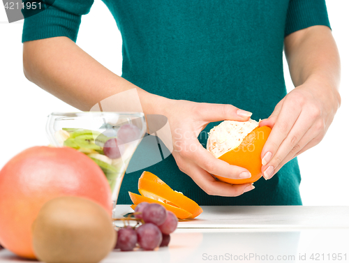 Image of Cook is peeling orange for fruit dessert