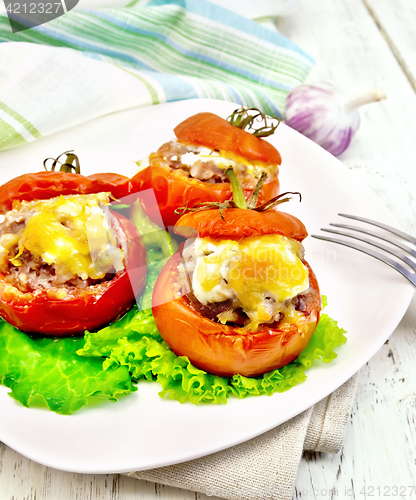 Image of Tomatoes stuffed with rice and meat with lettuce in plate on lig