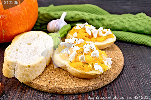 Image of Bruschetta with pumpkin and basil on dark board