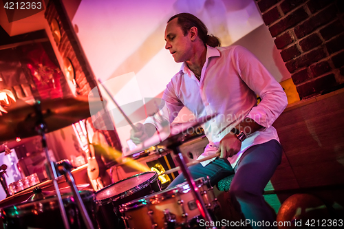 Image of Drummer playing on drum set on stage.