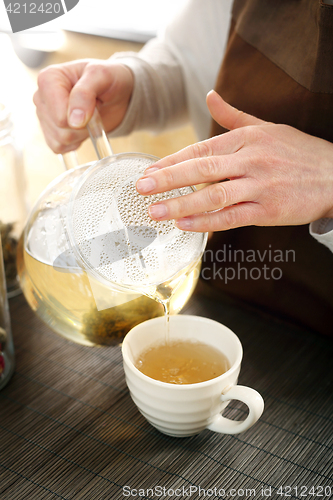 Image of Blooming tea. The waitress pours tea into a cup.