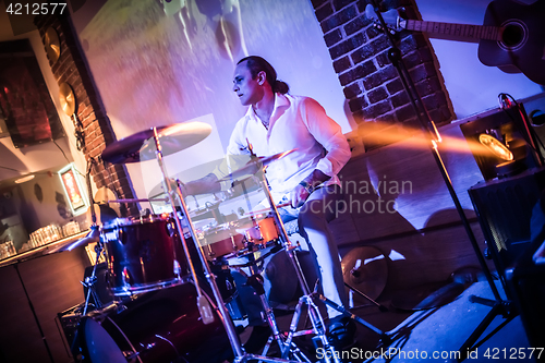 Image of Drummer playing on drum set on stage.