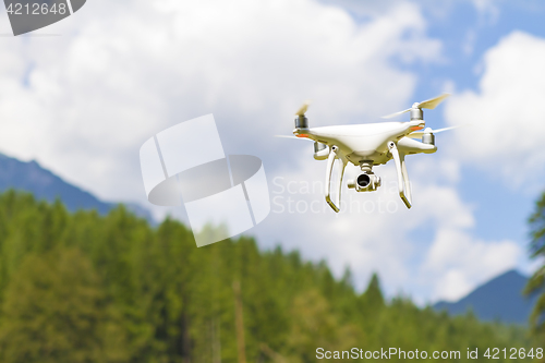 Image of White drone flying above mountains.