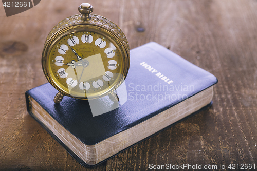 Image of Holy Bible and old alarm clock on wood table