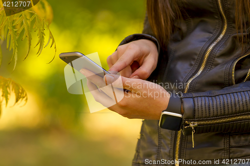 Image of Young girl using smart phone in the park