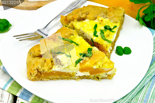 Image of Pie of pumpkin and cheese in white plate on light board