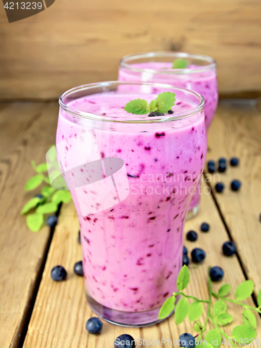 Image of Milkshake with blueberries in two glasses on board