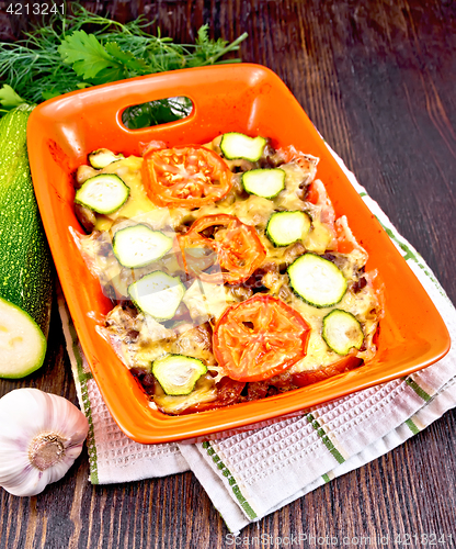 Image of Casserole from minced meat and zucchini in brazier on dark board