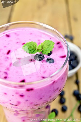 Image of Milkshake with blueberries in glass on wooden board