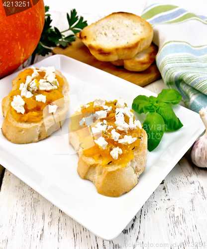 Image of Bruschetta with pumpkin and cheese in white plate on board