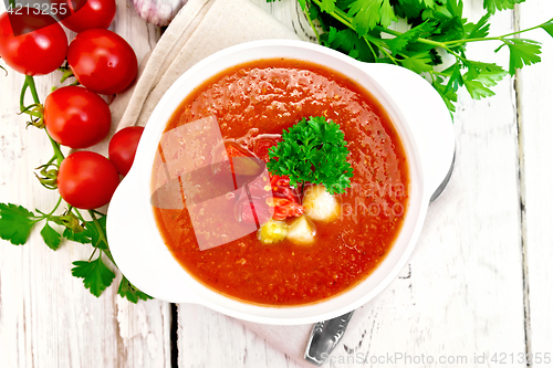 Image of Soup tomato in white bowl with vegetables and parsley on board t