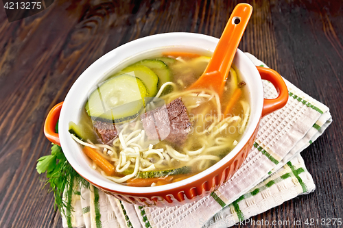 Image of Soup with zucchini and noodles in bowl on towel