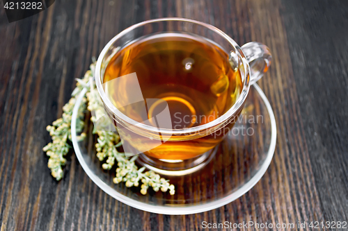 Image of Tea with gray wormwood in glass cup on dark board