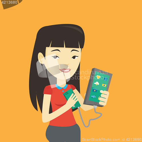 Image of Woman reharging smartphone from portable battery.
